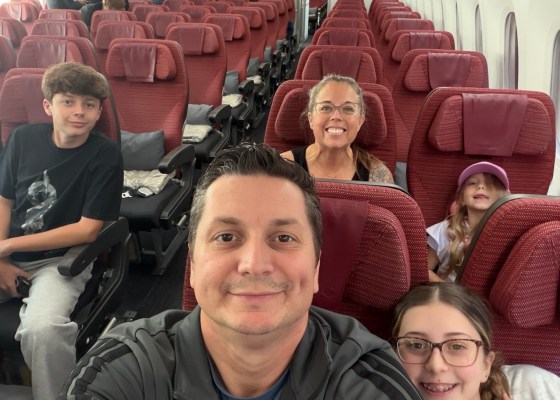The Nickolaou family together in airplane seats with red headrests