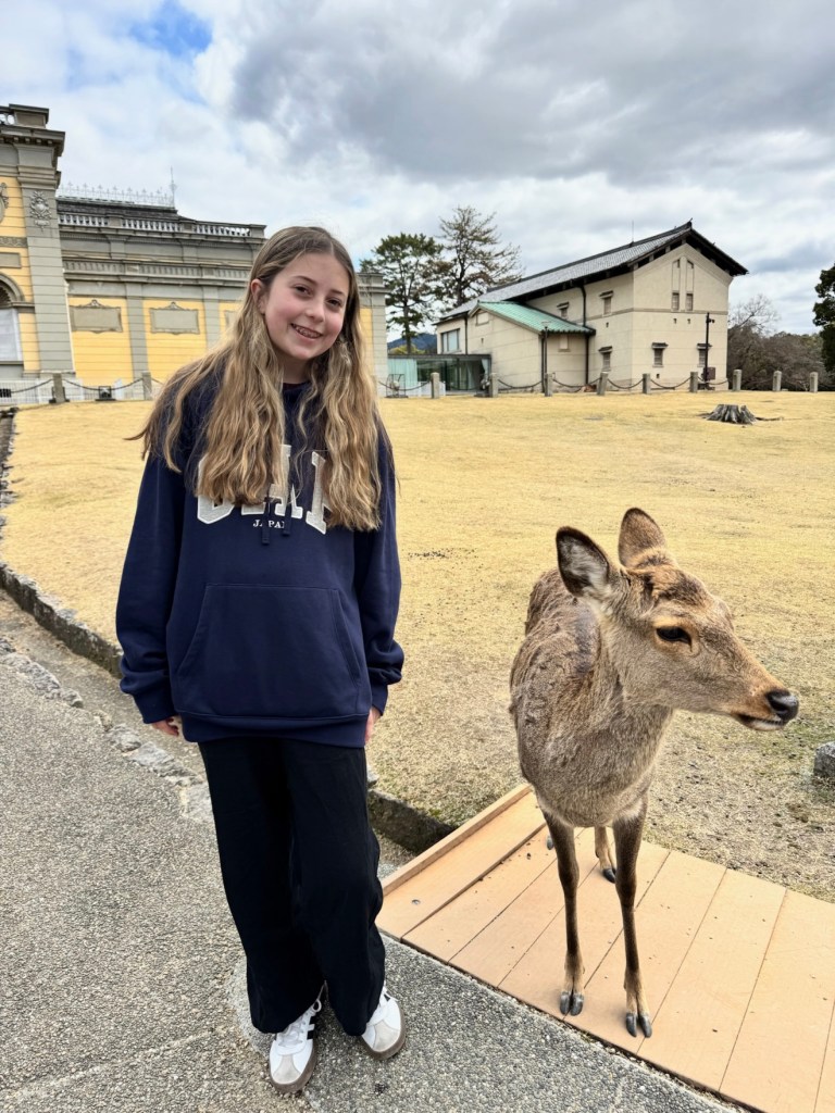 Kennedy standing and smiling next to a deer in Nara Park