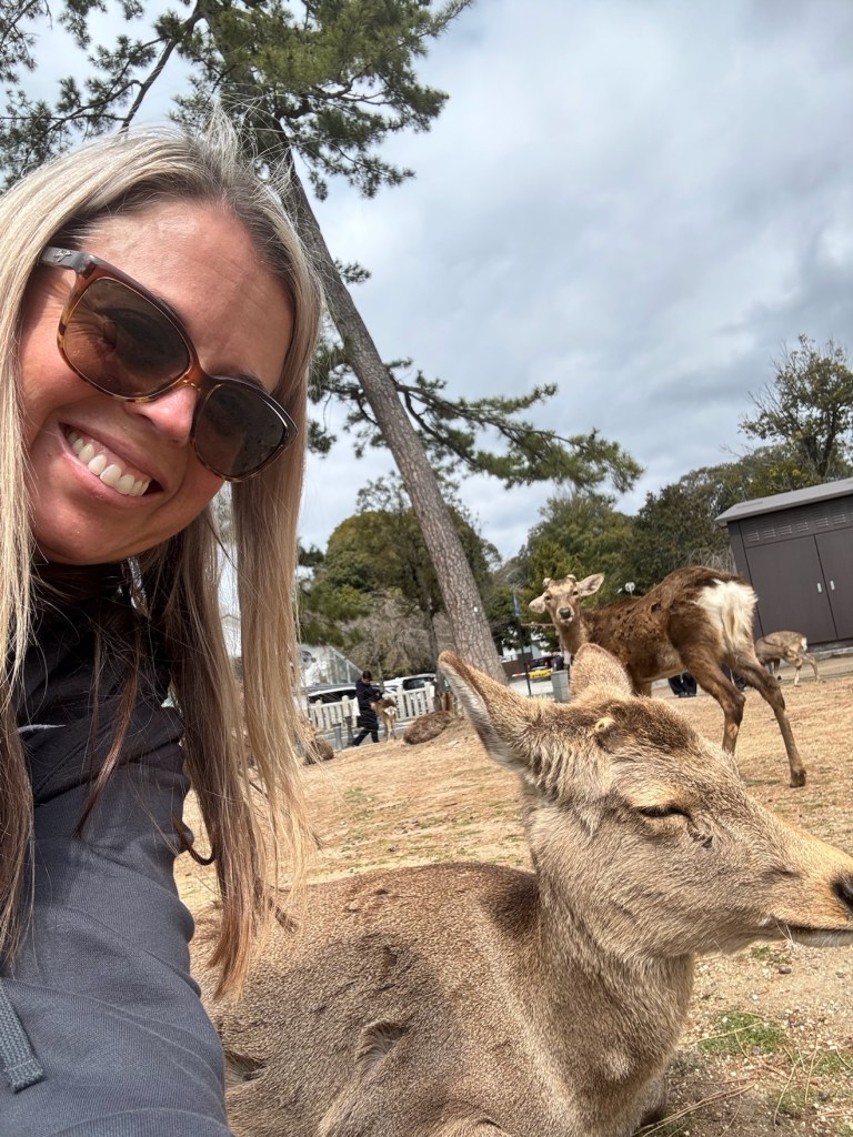 Devon taking a selfie next to a resting deer in Nara Park