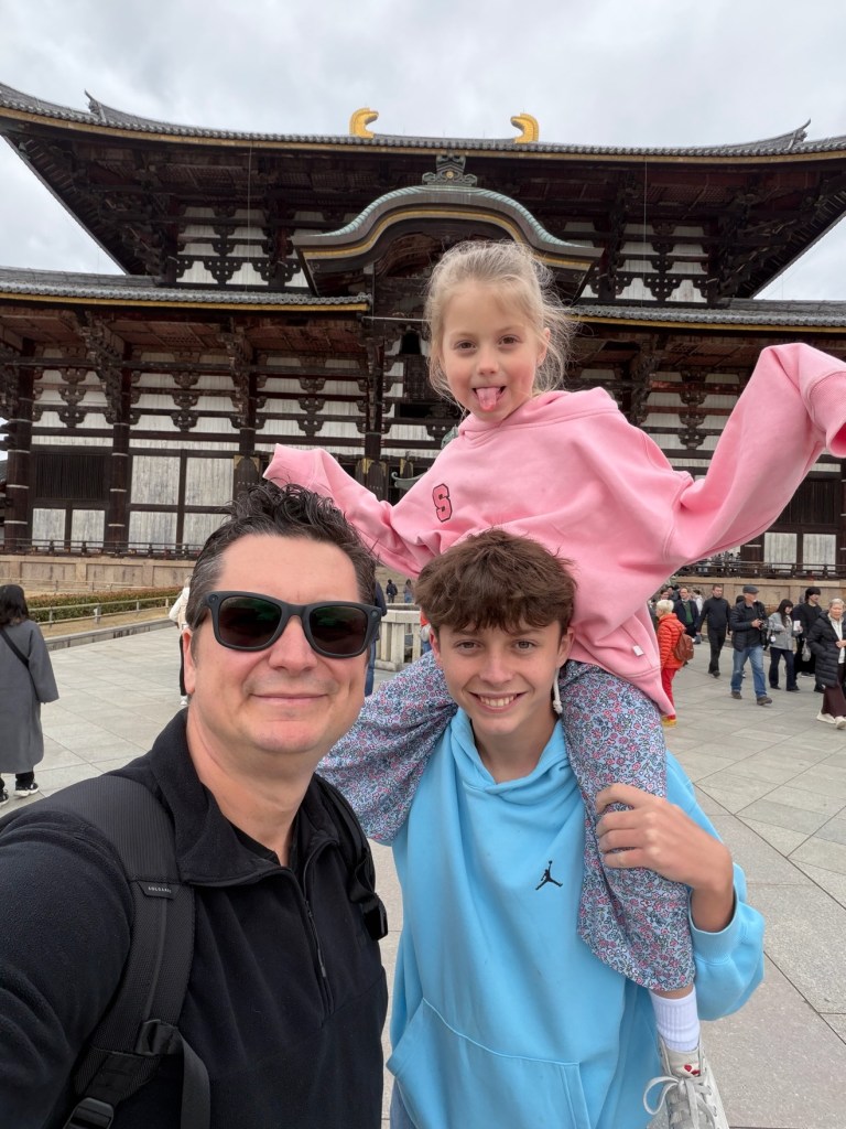 Niko selfie with Maddox carrying Sawyer on his shoulders in front of the Todai-ji hall