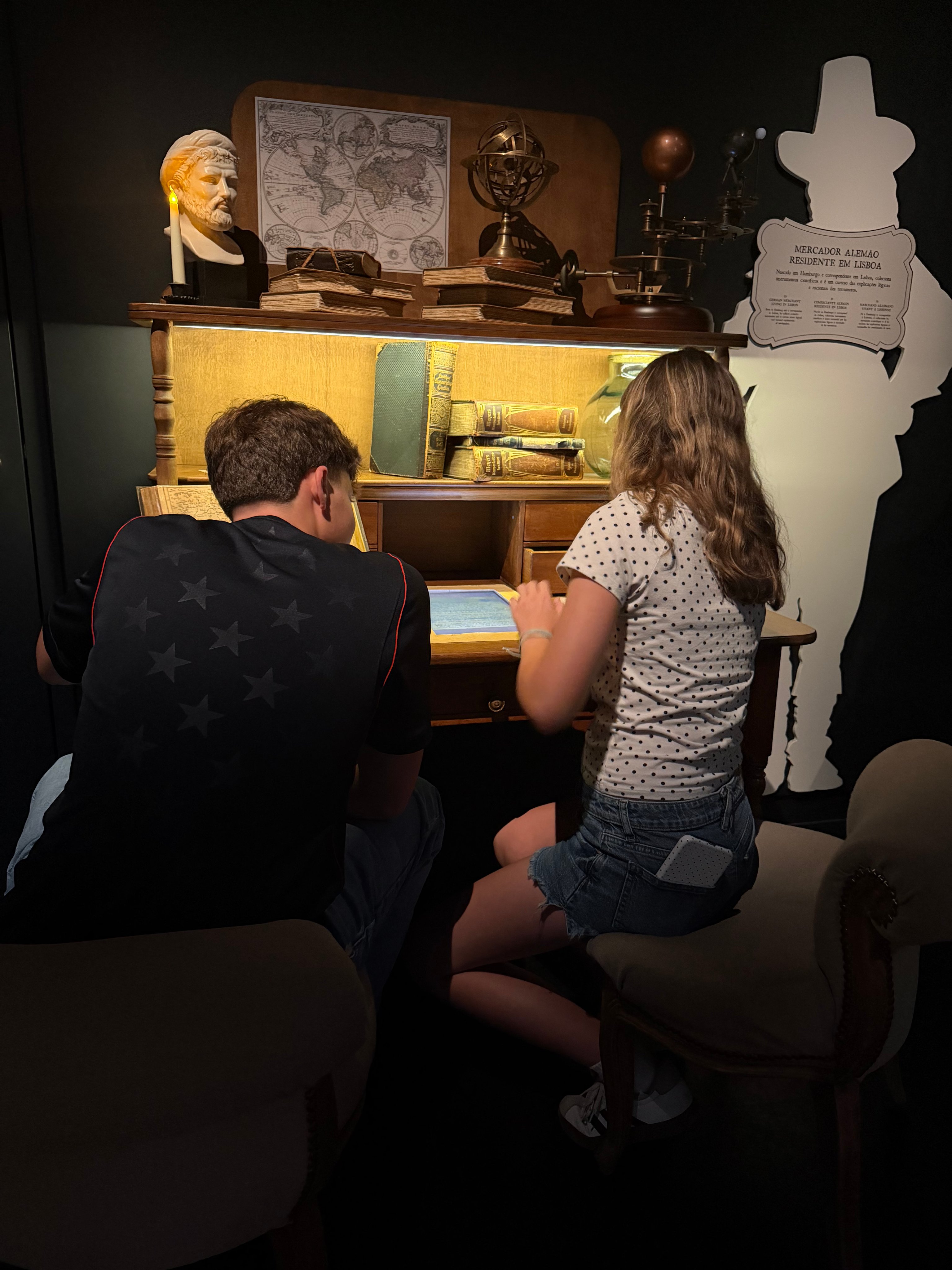 Boy and girl hunched over the Professor's lit desk